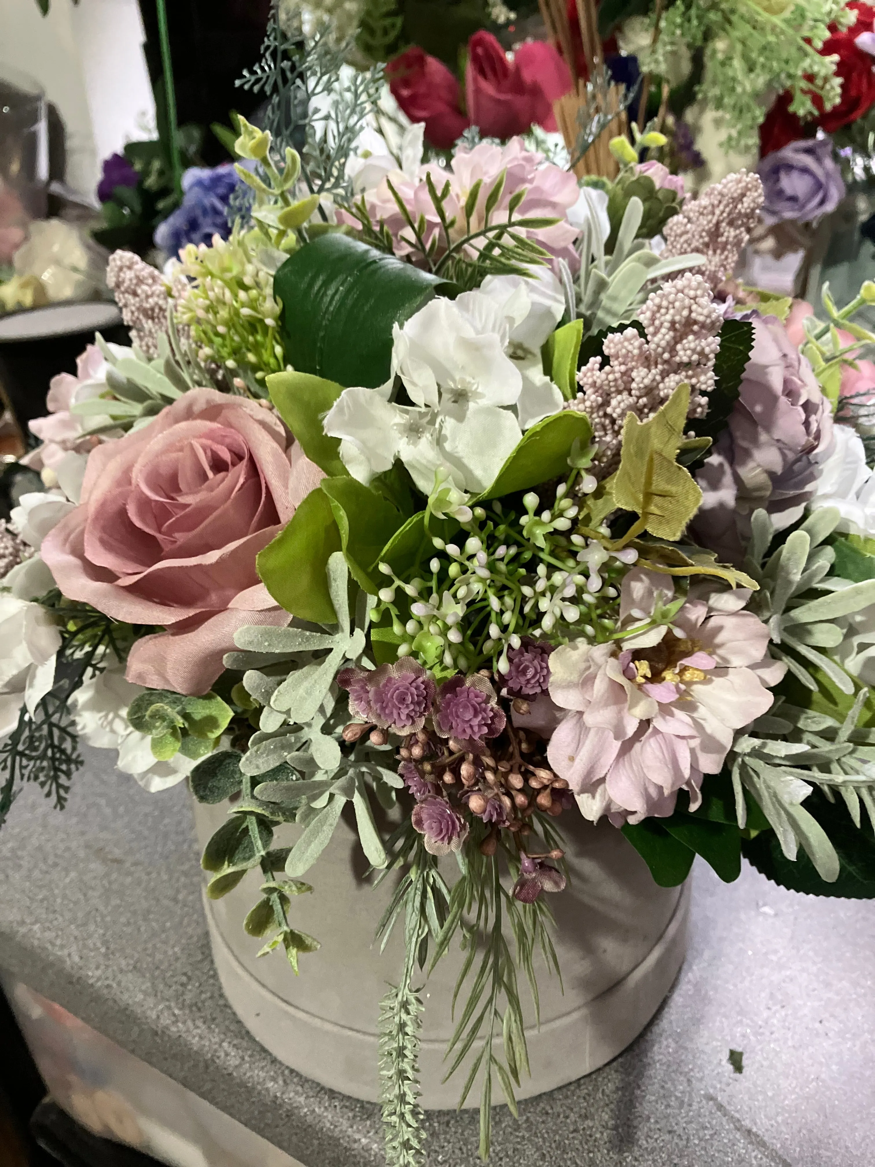 A flower arrangement of ivory hydrangea & pink roses in hatbox