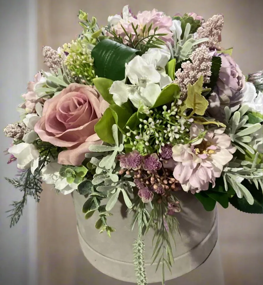 A flower arrangement of ivory hydrangea & pink roses in hatbox