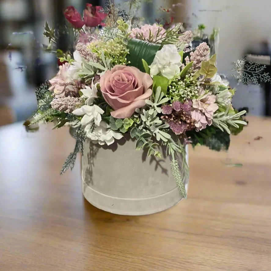 A flower arrangement of ivory hydrangea & pink roses in hatbox